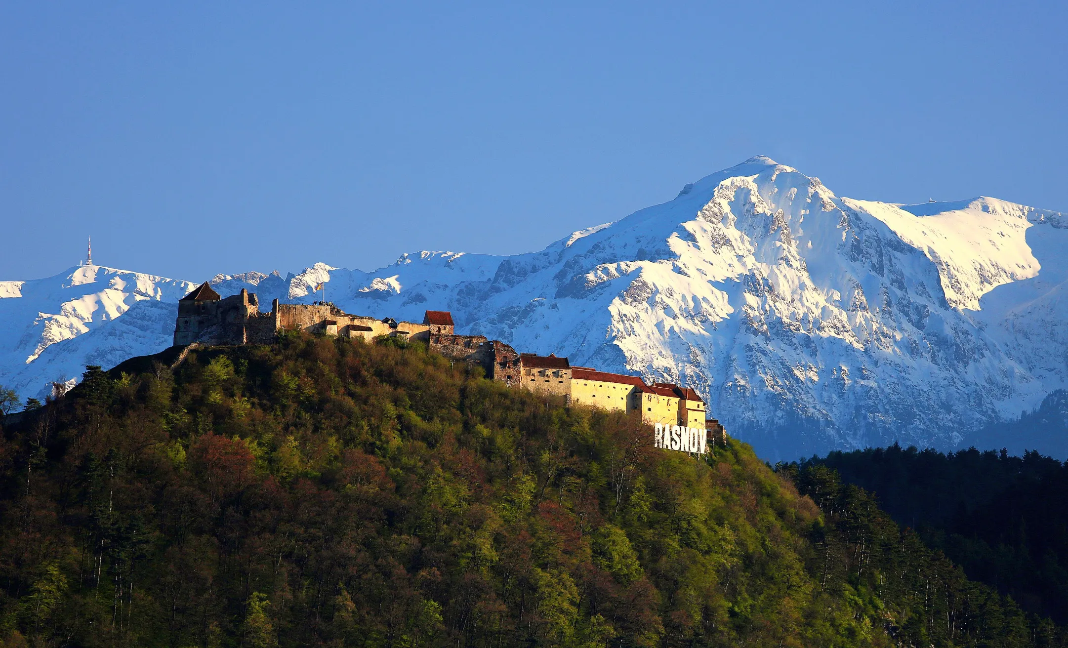 Rasnov Fortress in Transylvania, Romania, set against a backdrop of snowy mountains, for a general geography quiz.