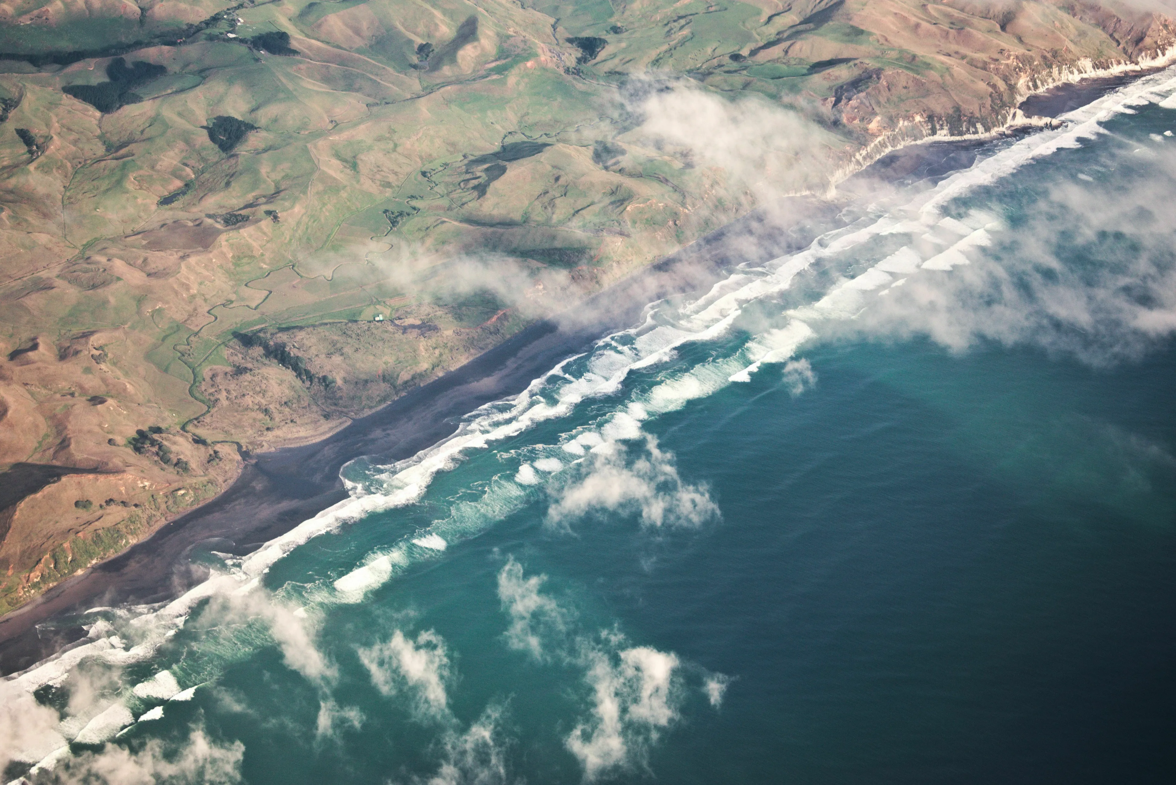 An aerial view of a coastline with waves, representing a country with the longest coastline, for a geography knowledge quiz.