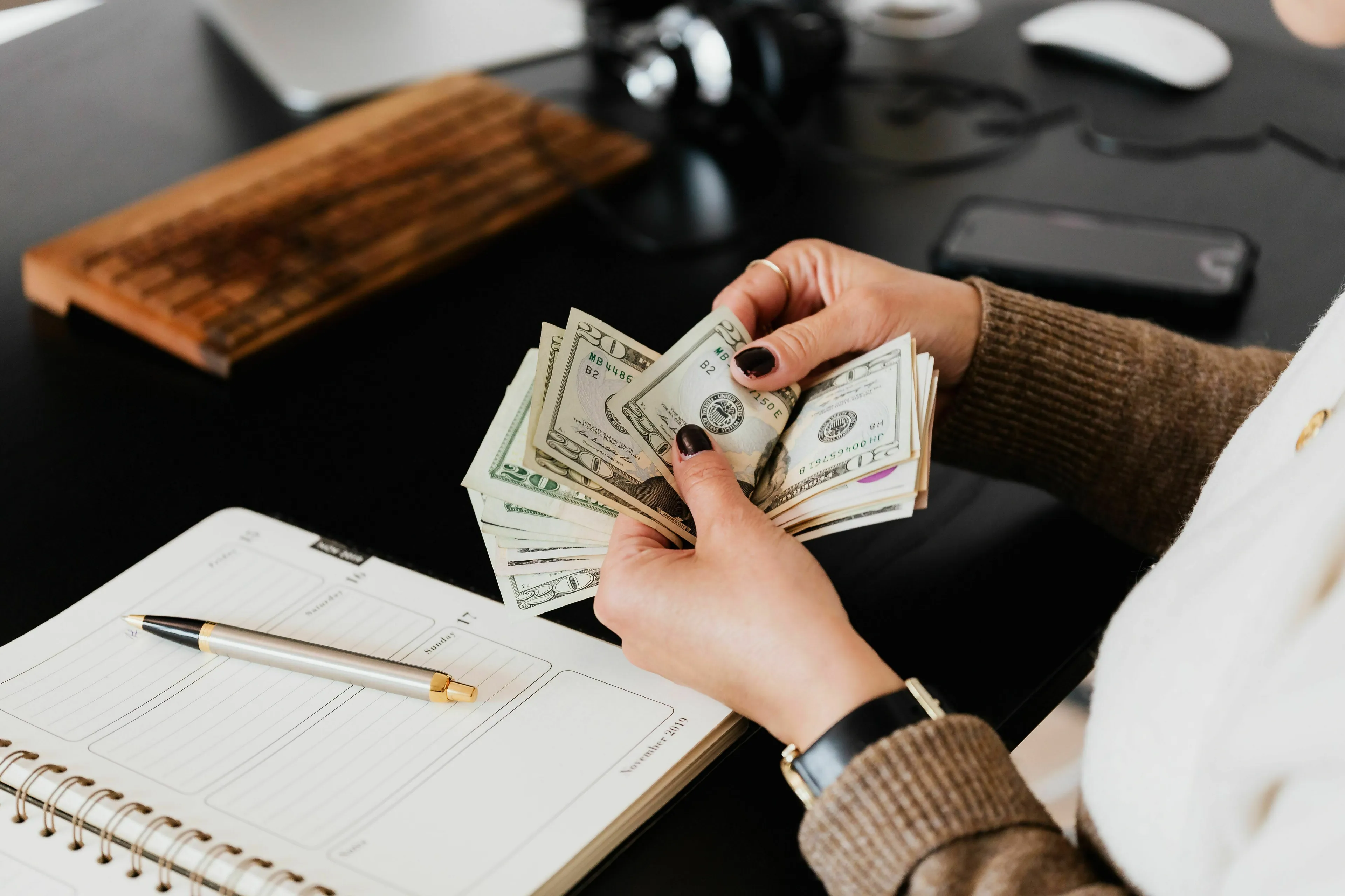 Hands counting US dollar bills, considering your ideal way to spend a paycheck.