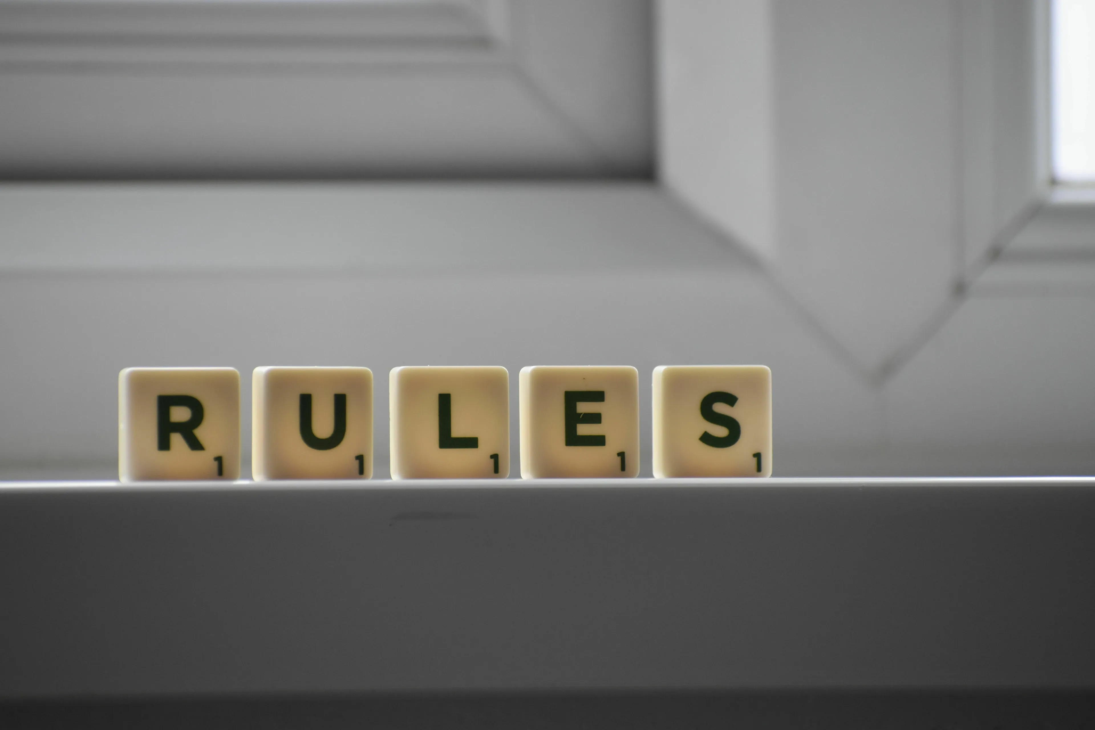 Scrabble tiles spelling RULES on a ledge, illustrating how you handle rules you disagree with.