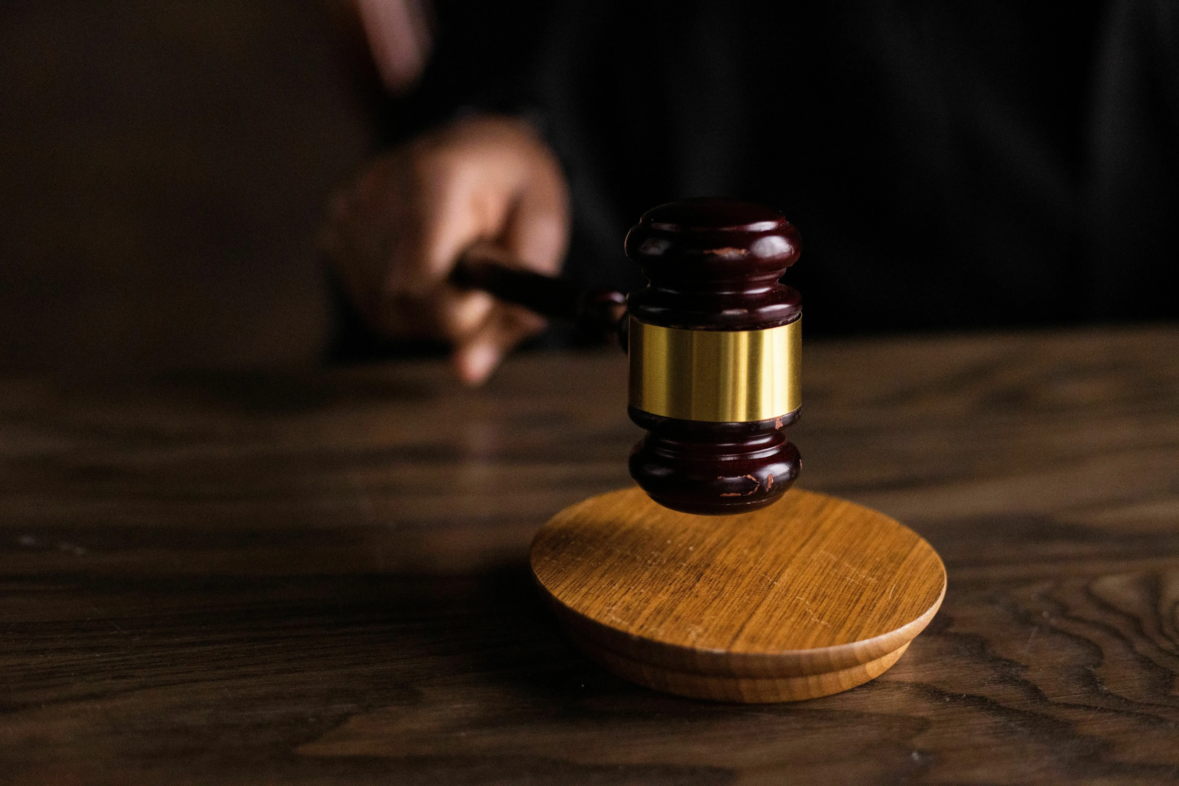 A hand holds a gavel over a wooden block. The image reflects how one views authority.