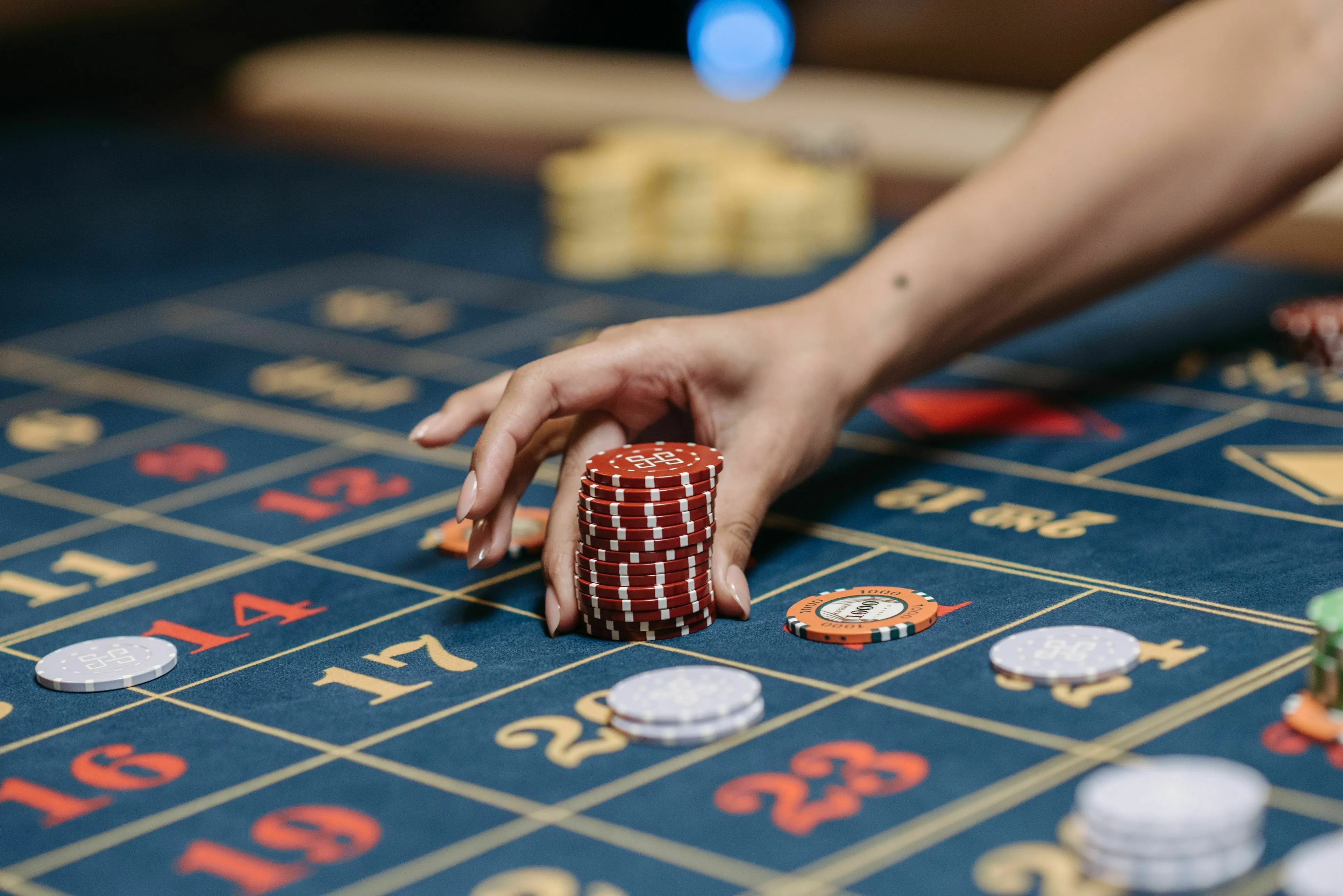 A hand placing a stack of red chips on a roulette table, representing a historical figure taking a risk.
