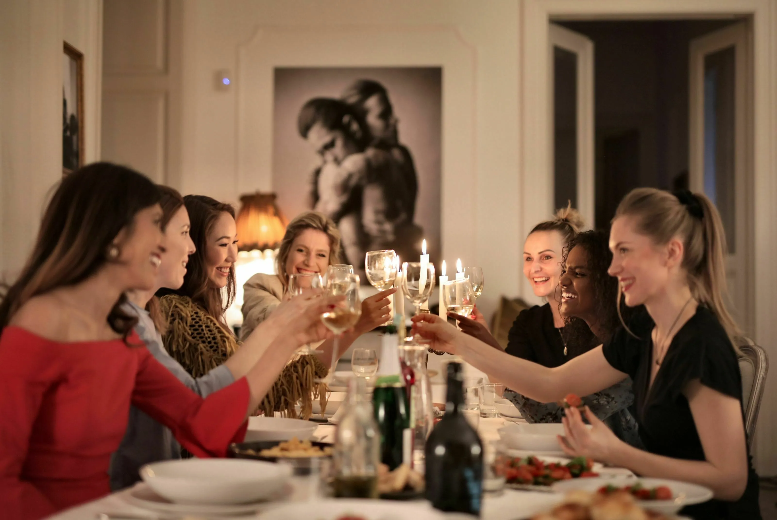 Women at a lively dinner party, toasting with wine glasses, depicting a historical figure at a big dinner party.