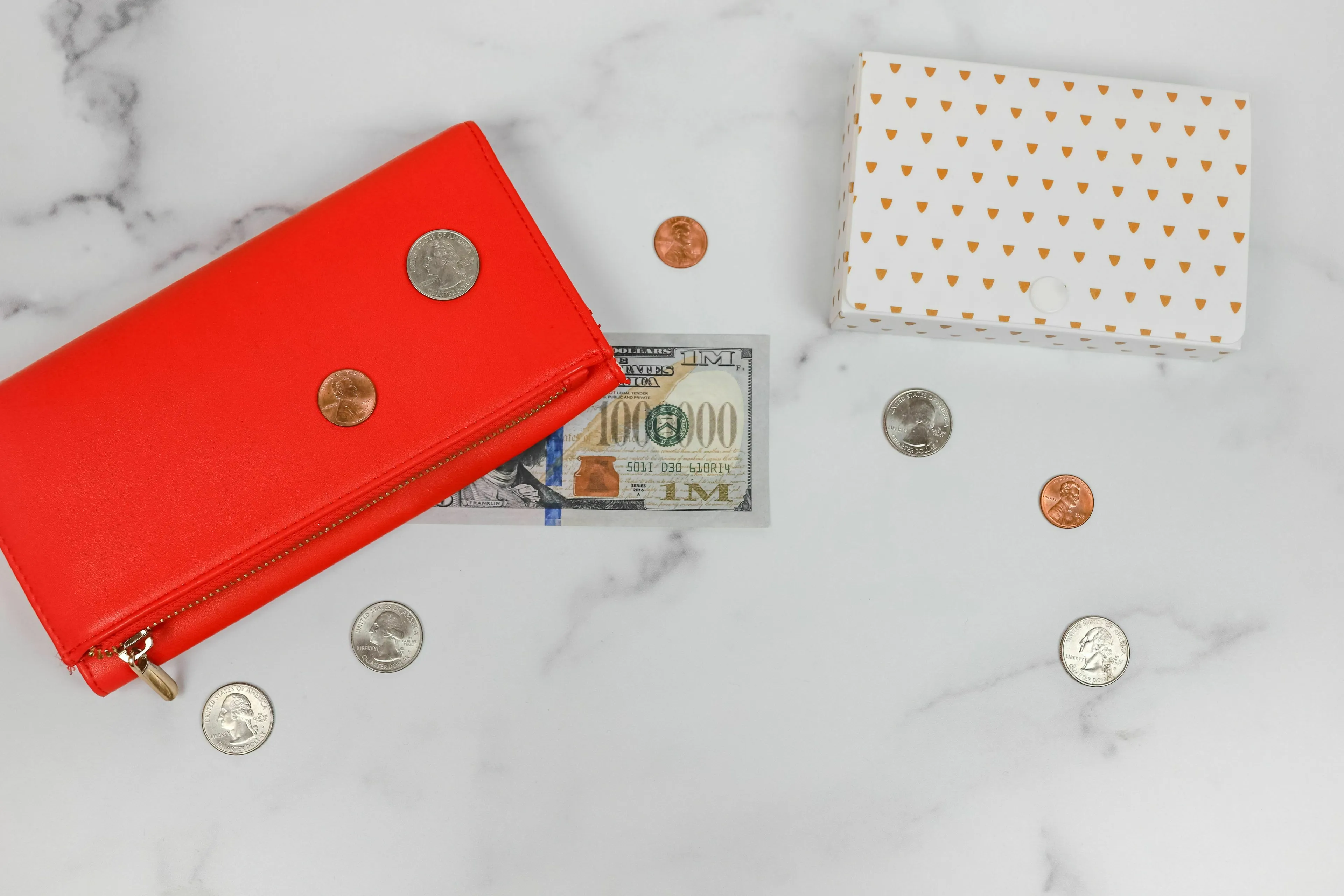 A red wallet, money, and coins on a marble surface, representing how a historical figure spends money.