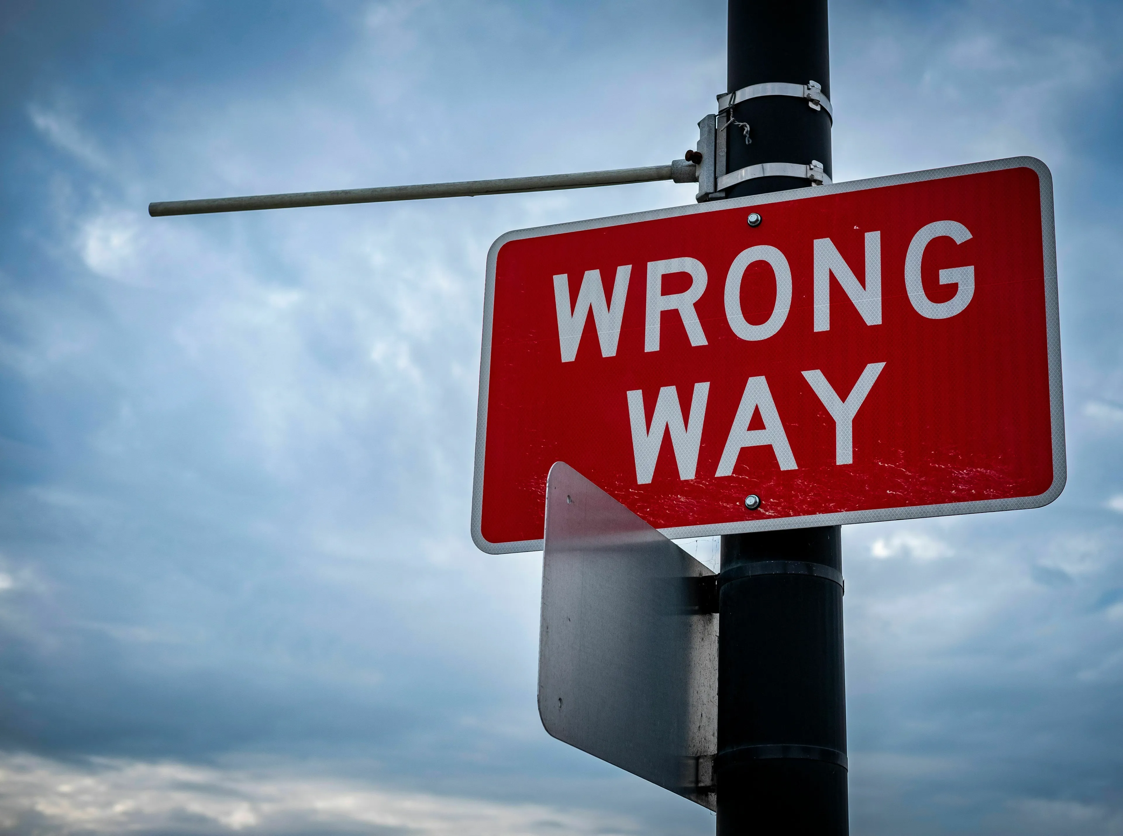 A red Wrong Way sign against a cloudy sky, illustrating how a historical figure handles being wrong.