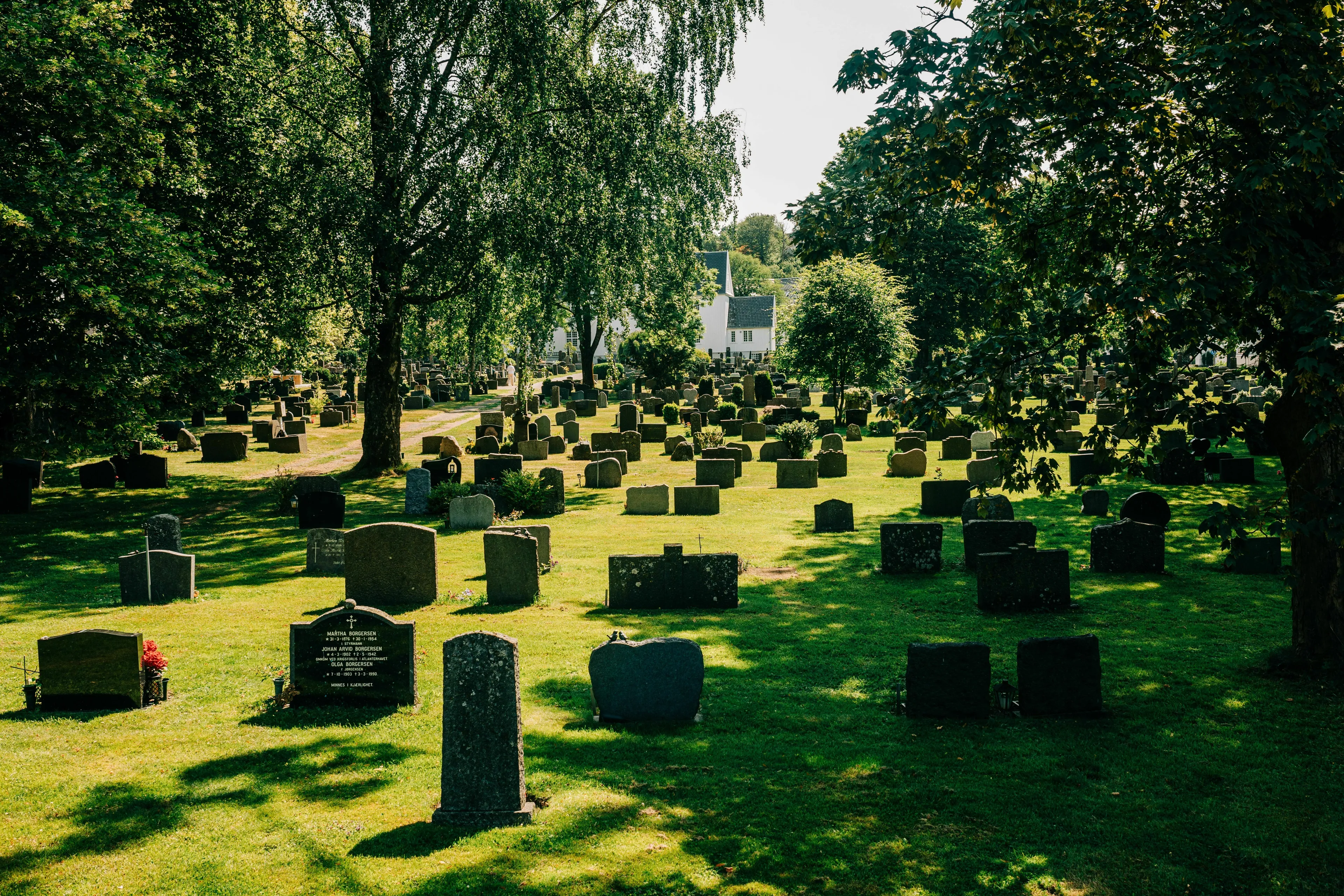 A graveyard with many headstones under green trees, representing the question: What would people say at your funeral?