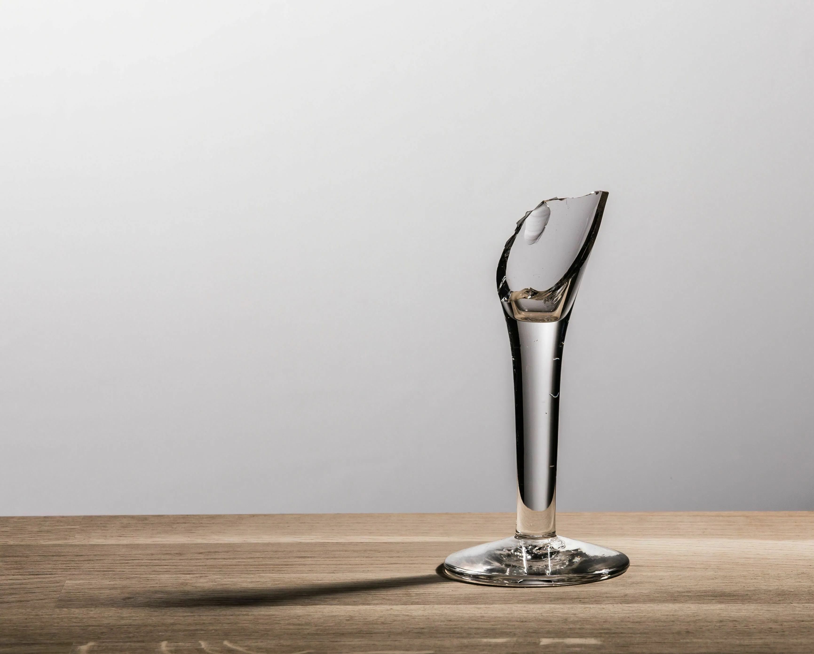 A broken wine glass on a wooden table, symbolizing the biggest flaw in a Historical Figure quiz.