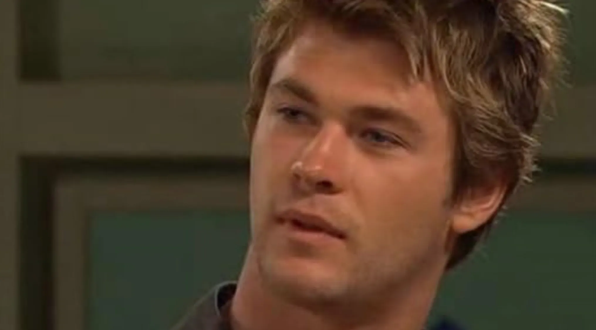 A close-up of a young Chris Hemsworth as a soon-to-be celebrity, looking to the side with a serious expression.