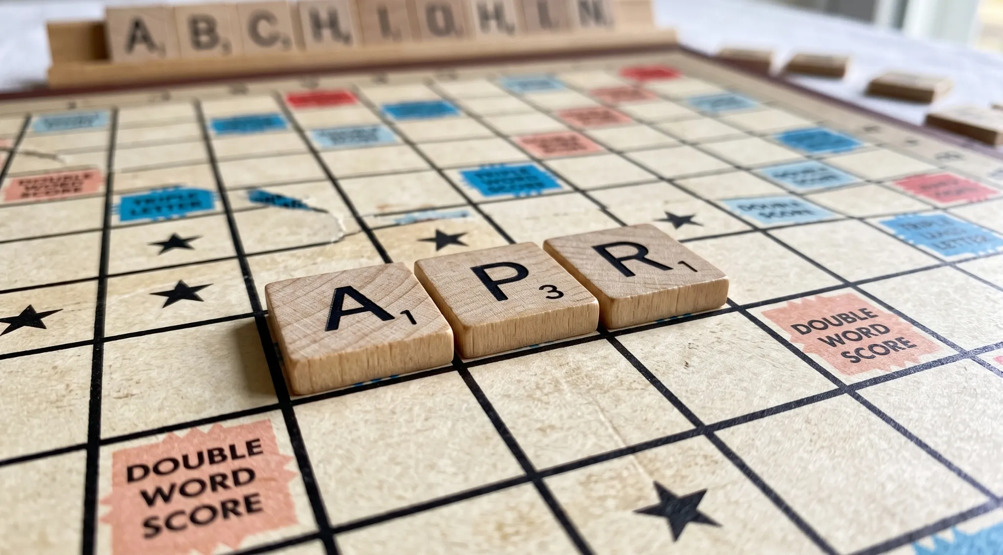 Scrabble tiles spell APR on the game board. This image relates to Home Economics and what APR stands for.