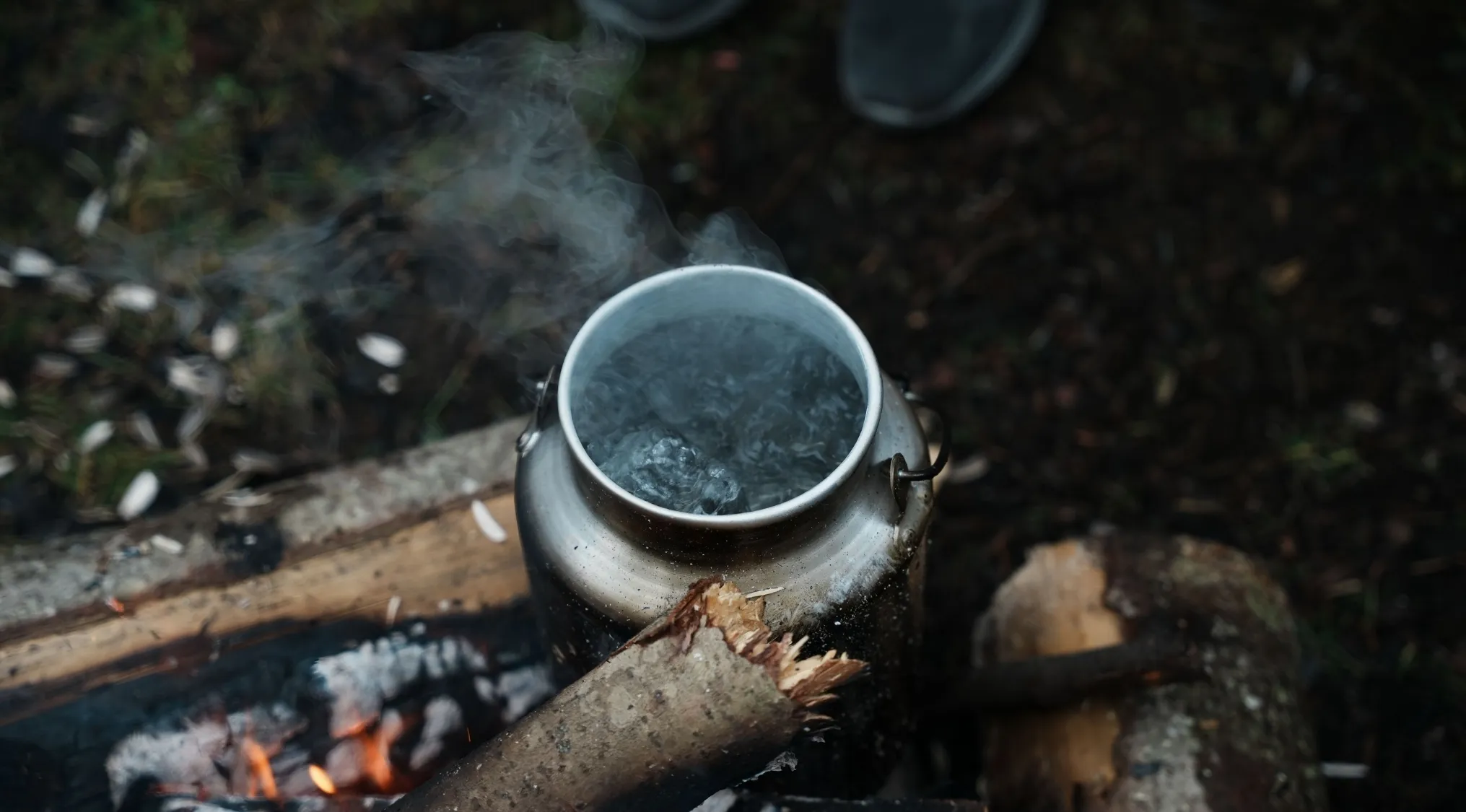 An outdoor pot of simmering water with steam rising, illustrating the difference between simmering and boiling.
