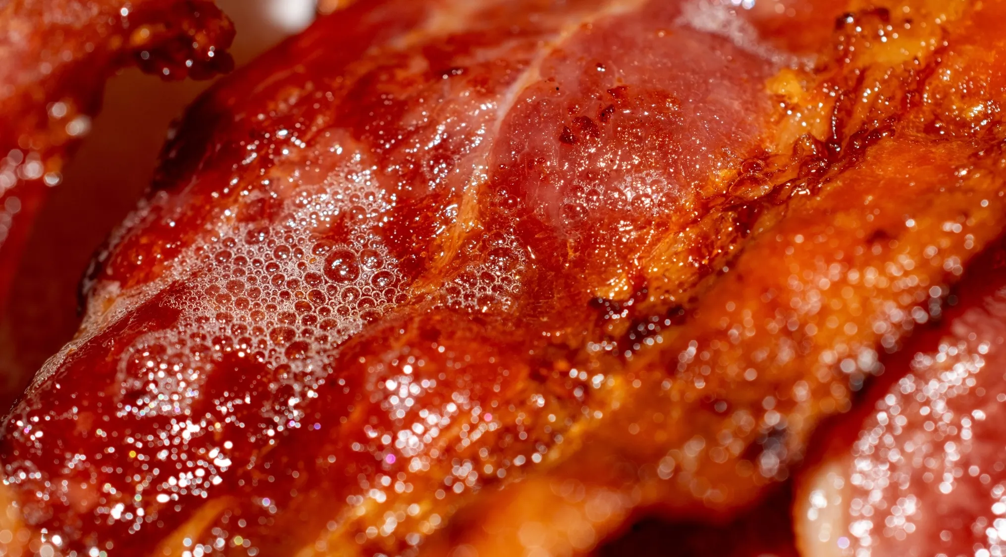 Close-up of bubbling, rendered bacon grease, showcasing its rich texture. Ideal for discussing bacon grease disposal.