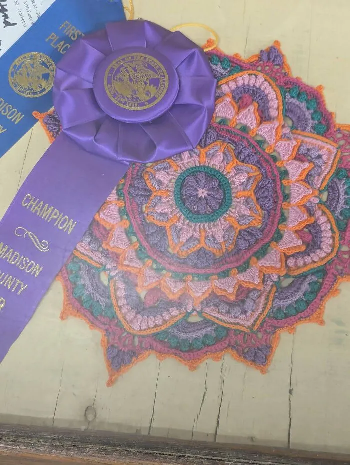 Intricate crochet mandala with award ribbons representing creative crochet project