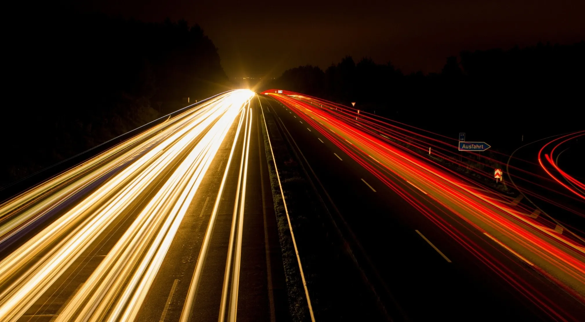 Long exposure shot of a highway at night, showing bright light trails from moving objects. Property of a moving object.