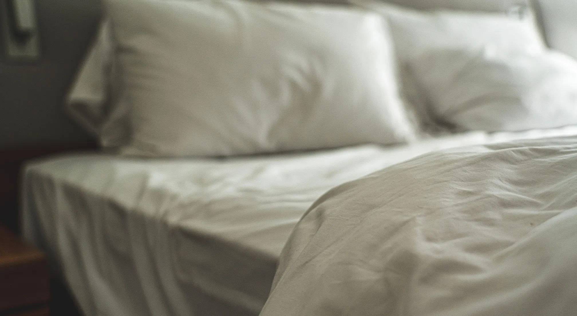 A close-up of a bed with white sheets and pillows, emphasizing the comfort and cleanliness, relevant to bed bugs discussions.