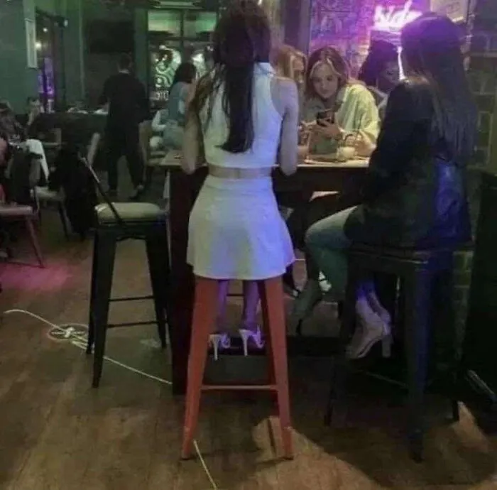 A woman sitting on a high stool in a bar, a real photo that makes your brain question reality.