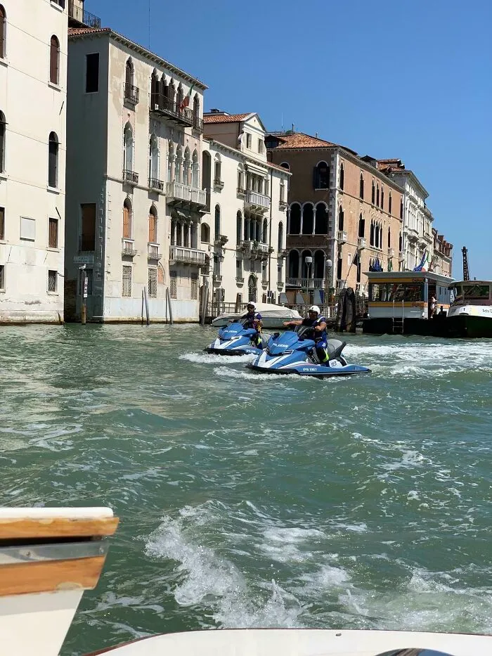 Two jet skis on a Venice canal, featuring real photos that make your brain question if they were edited.