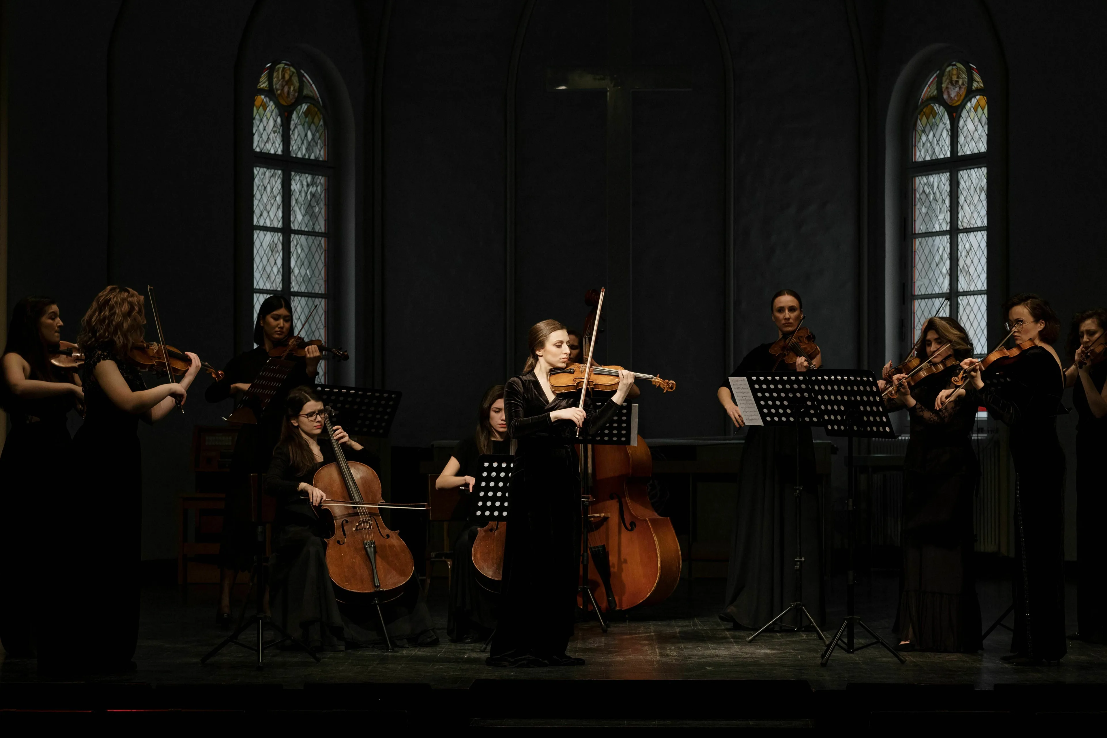 A string orchestra performing, featuring violins, cellos, and bass in a classical music setting.
