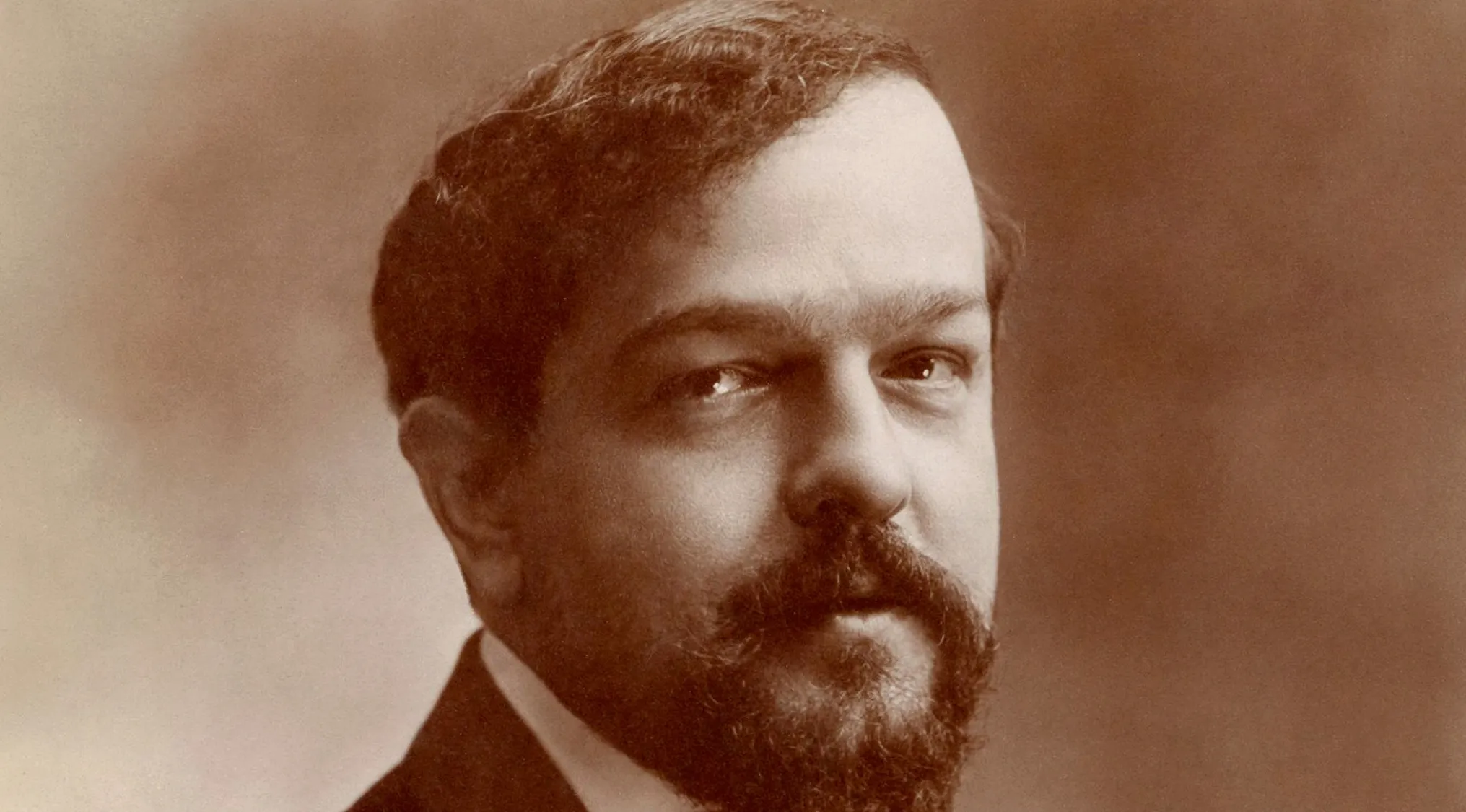 Sepia-toned portrait of composer Claude Debussy, known for his classical music pieces.