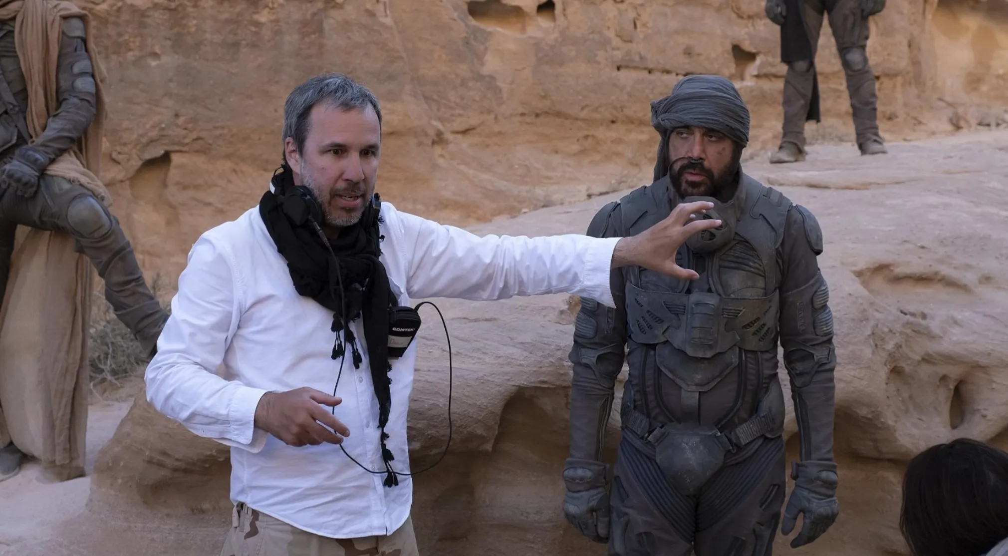 BTS image of a director talking to an actor in costume, on a desert film set. Guess the movie franchise.