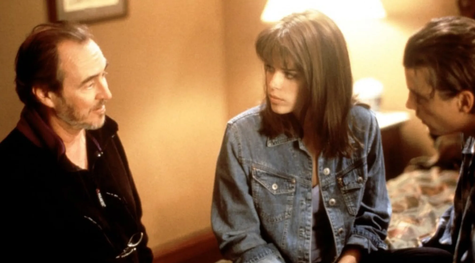 A BTS image showing a man, a woman in a denim jacket, and another man in conversation. Guess The Movie.