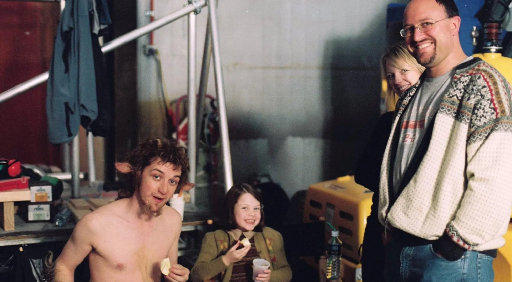BTS image shows actors and crew on set. A man with faun ears and a girl smile at the camera. Guess the movie.