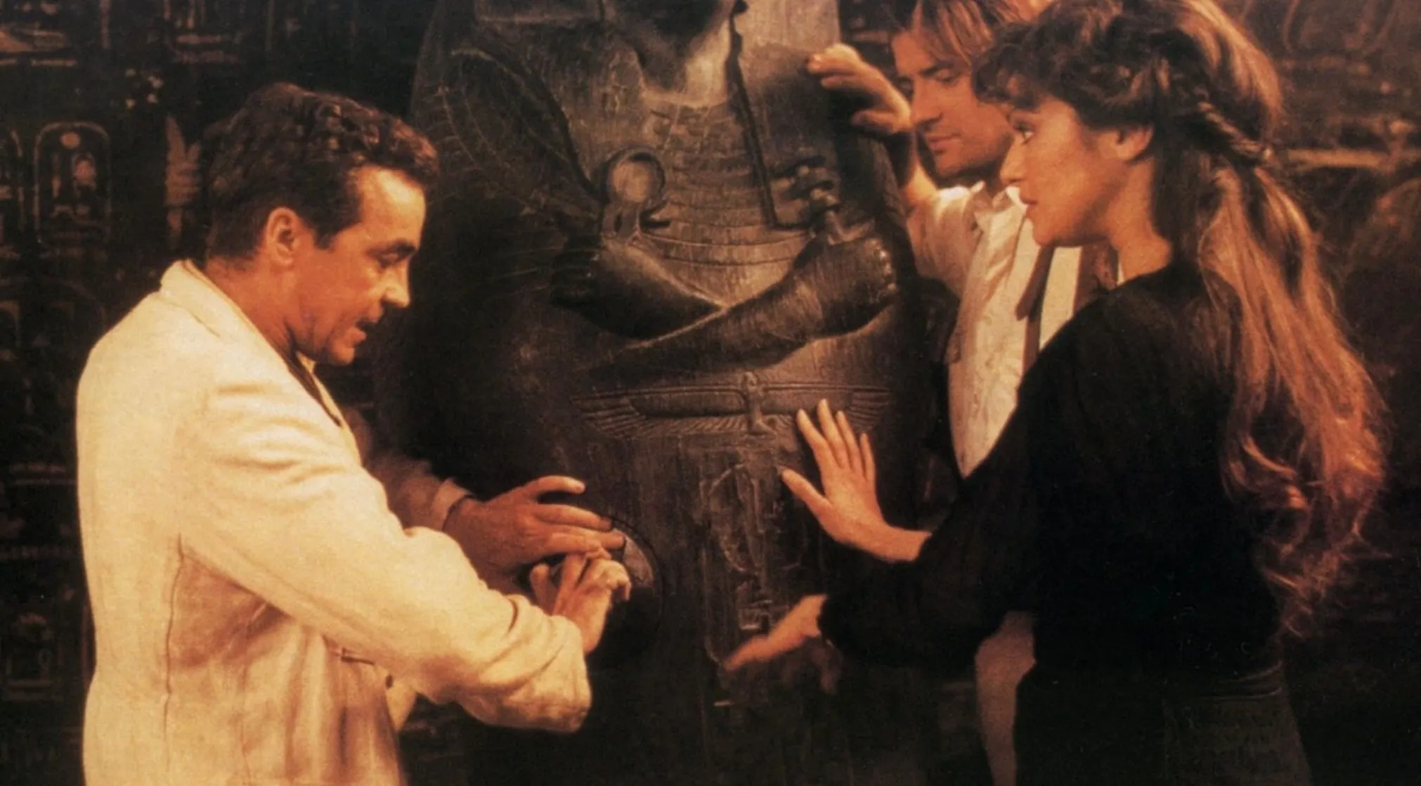Three individuals from a movie franchise touching an ancient-looking statue, guess the movie from the BTS image.