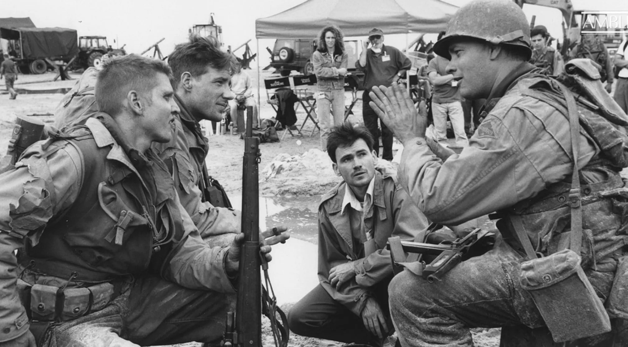 Black and white BTS image from a movie set. Soldiers in uniform converse while crew members observe. Guess the movie.