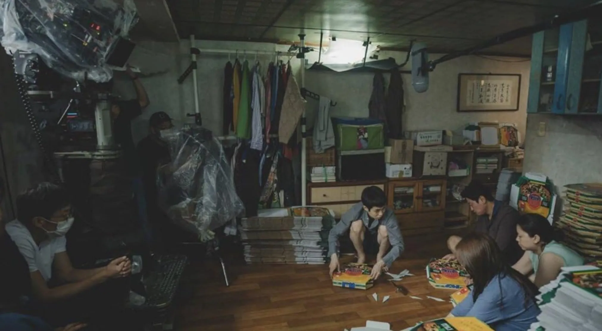 Guess the Movie from this BTS with crew and actors in a low-lit room, surrounded by film equipment.