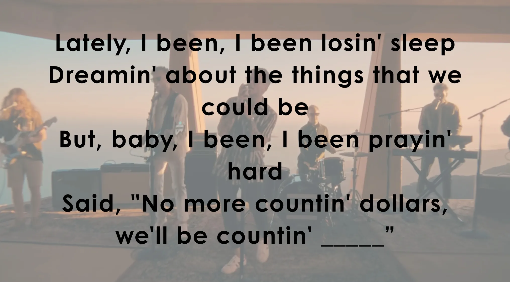 A band performs live, with song lyrics displayed asking users to finish famous music lyrics by completing the missing word.