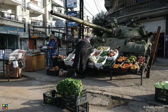 Award-worthy photo of a street market set up around a tank, telling a poignant story without words.