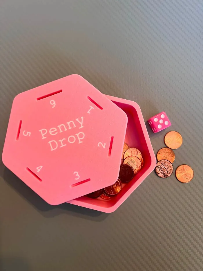 A pink hexagonal Penny Drop game with a die and coins, a cool and useful 3D printed game.