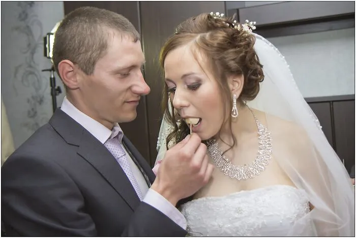 A groom feeding his bride in one of many funny wedding photos, capturing a silly moment.