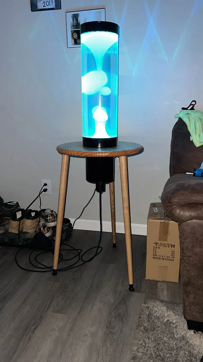 A glowing blue lava lamp, a cool thing created with a 3D printer, sitting on a wooden table.