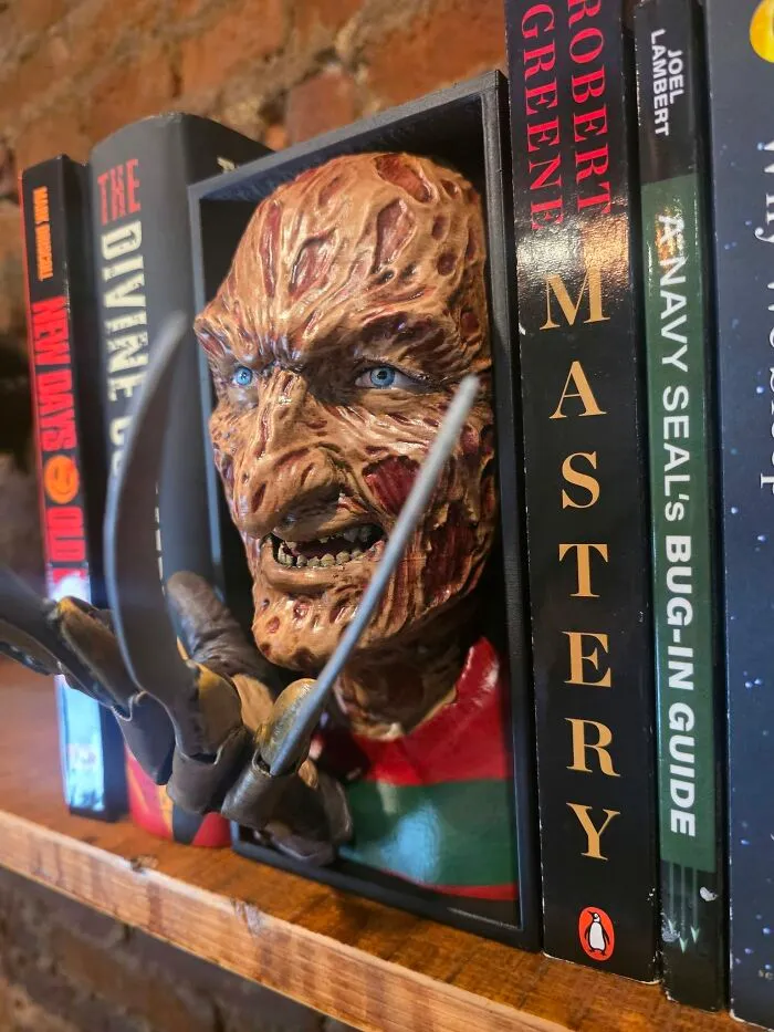 A Freddy Krueger 3D-printed bookend on a shelf, showcasing a cool and useful creation with a 3D printer.