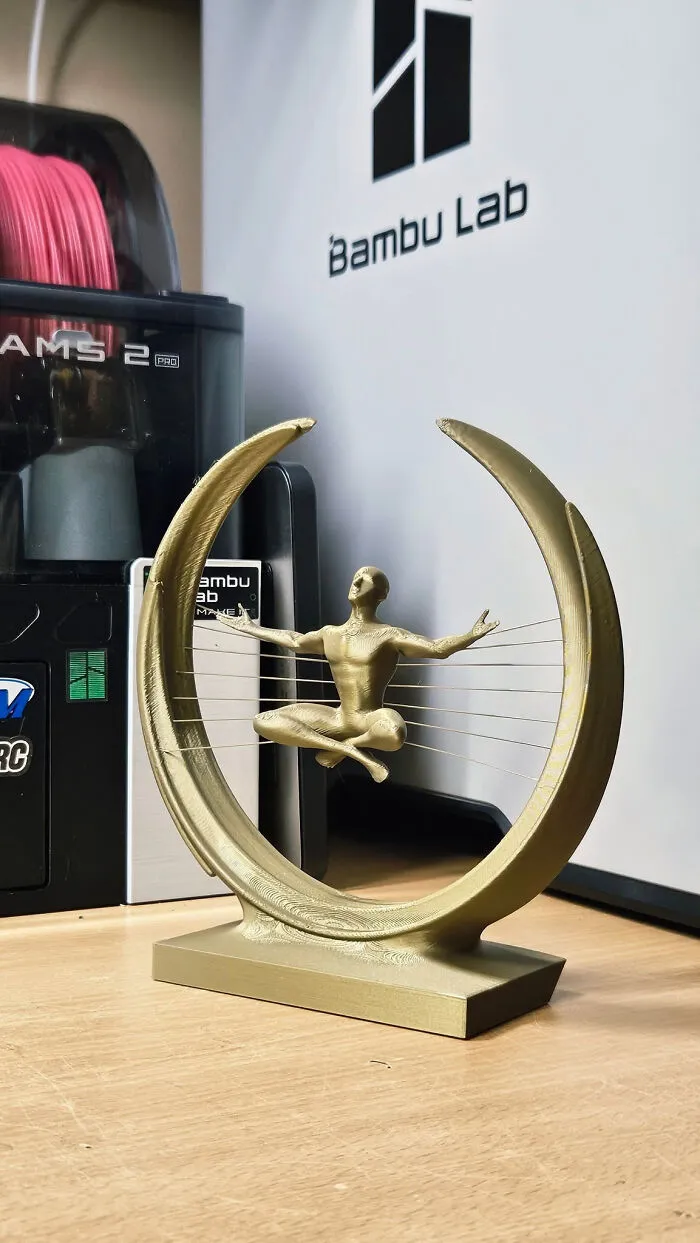 A gold 3D printed figure meditating within a circular frame, cool and useful things created with a 3D printer.