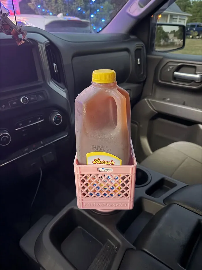 A gallon jug of iced tea in a pink miniature crate, a useful thing created with a 3D printer, in a car console.