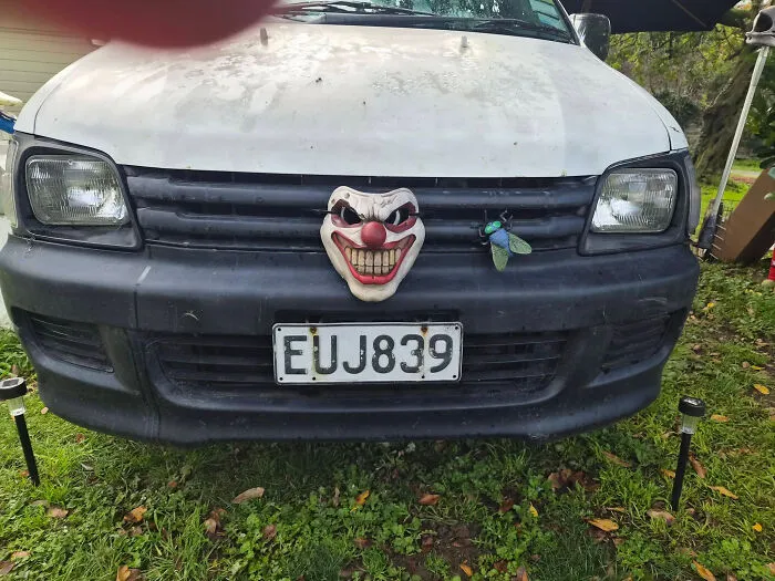 A white van with a scary clown face and a large green fly attached to the front grill, a unique 3D printer creation.