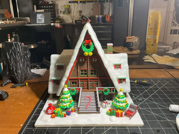 An intricate 3D printed Christmas house diorama with snow, trees, and presents, demonstrating cool things created with a 3D printer.