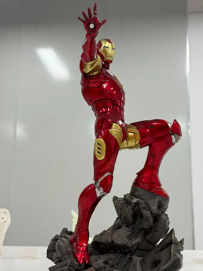 An impressive 3D printer creation of an Iron Man statue in a dynamic pose, showcasing red and gold armor.