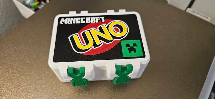 A white Minecraft UNO card box, a useful thing created with a 3D printer, on a brown surface.