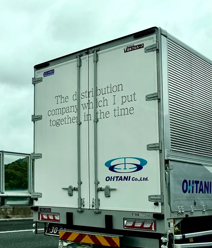 The back of a delivery truck in Japan with text that reads 'The distribution company which I put together in the time,' an example of getting lost in translation.