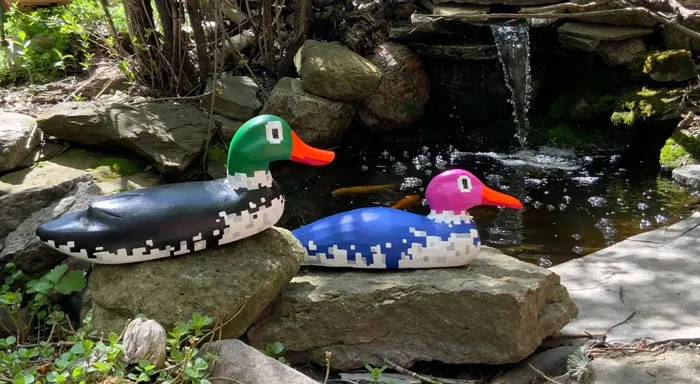 Creative pixelated duck decoys turning old junk into something worth keeping near a pond.