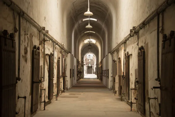 A long, dimly lit corridor in an old building, possibly an asylum, suggesting ghosts and hard to explain videos.
