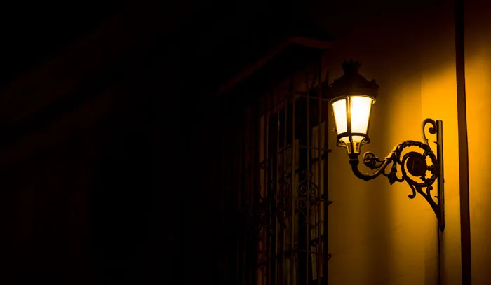 An old-fashioned street lamp casting a warm glow at night, symbolizing hard truths women learned.
