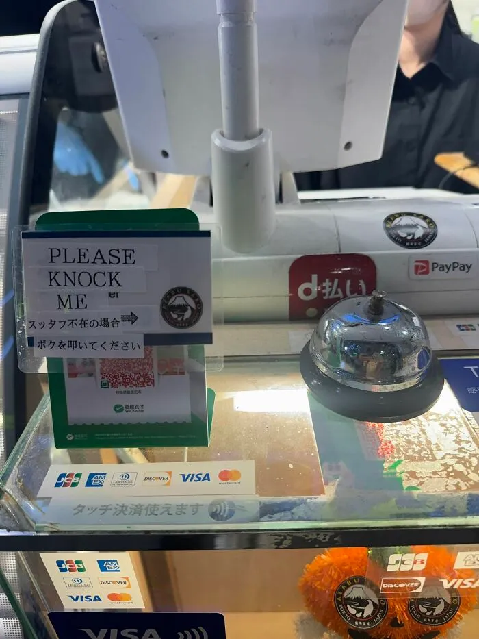 A counter in Japan with a bell and a sign, a hilarious example of getting lost in translation.