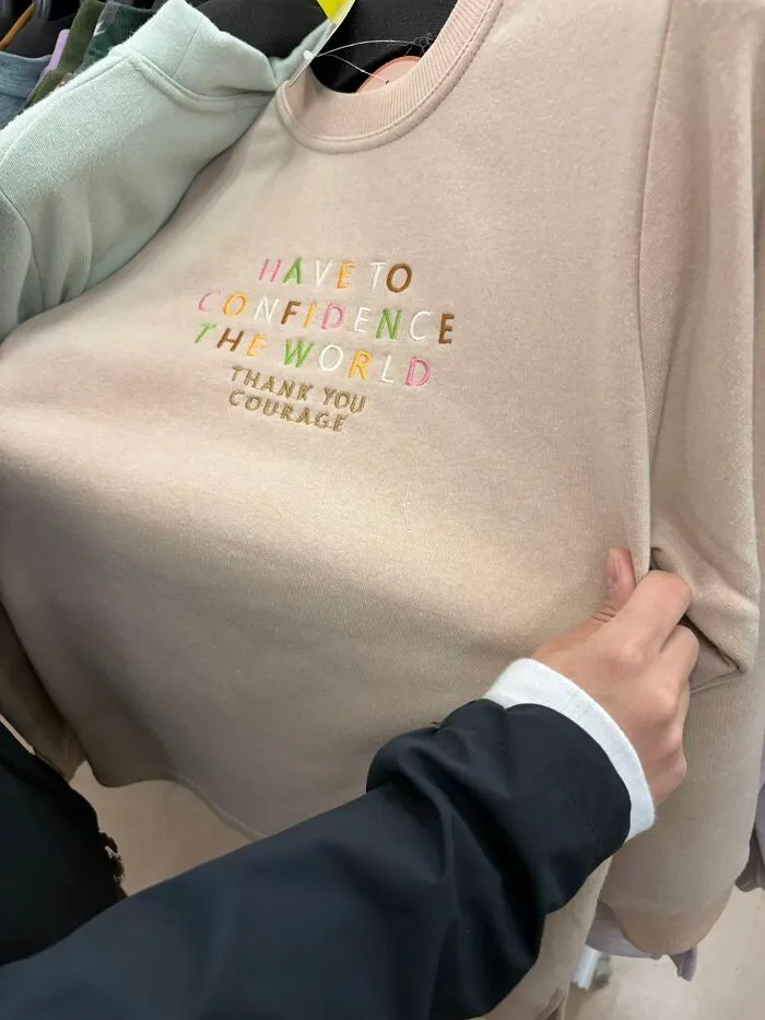 A person holding a sweater with a hilarious example of getting lost in translation, found in Japan.