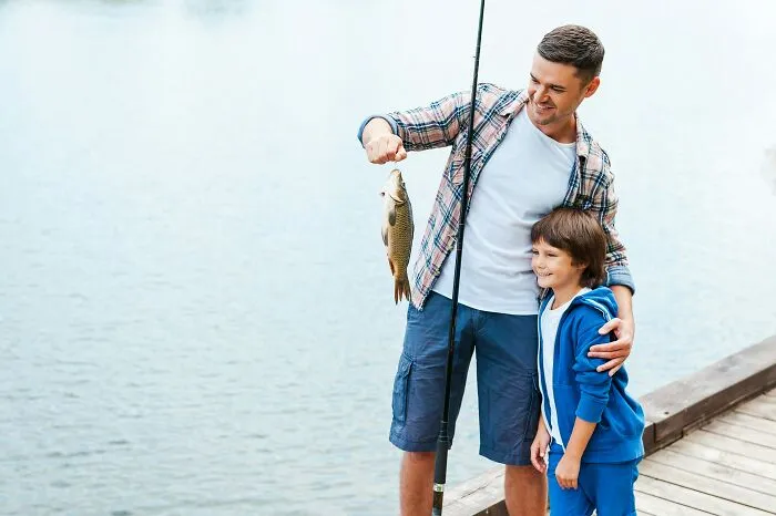 A father and son fishing, holding up a fish, reflecting questions kids asked parents.