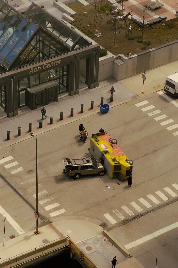 Dramatic color photo of an overturned yellow vehicle and a damaged car on a city street, capturing the world.