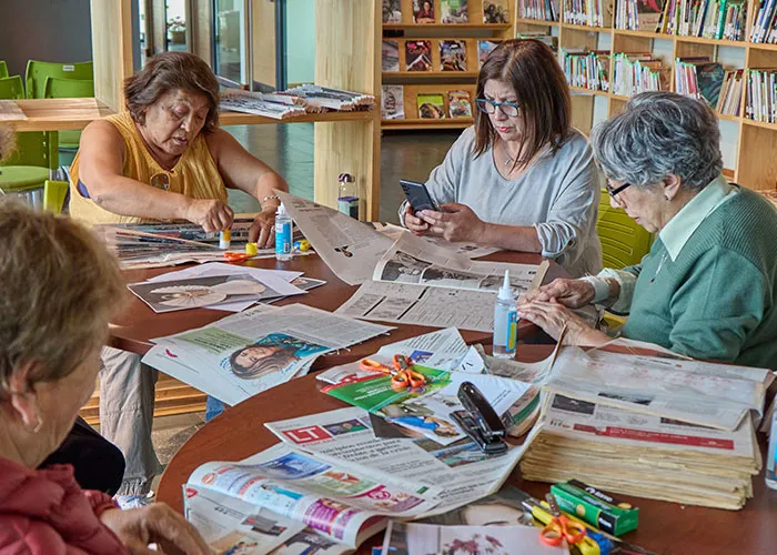 Older generations women creating collages from newspapers, a social activity many have stopped doing.