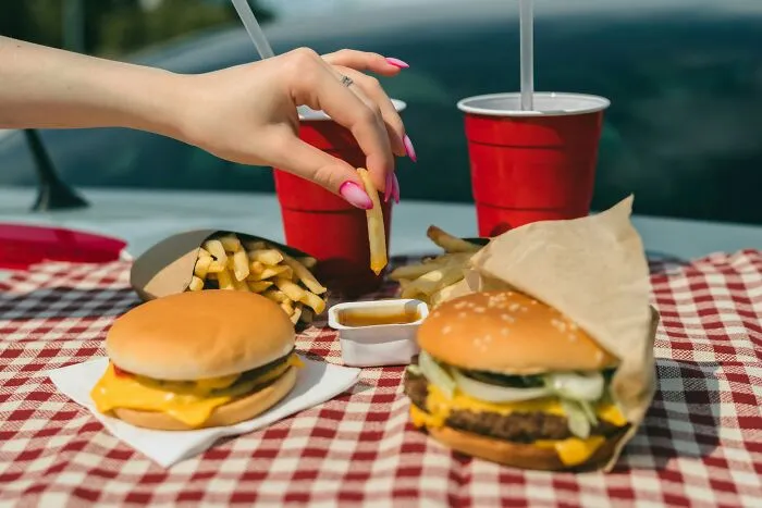 A hand reaches for a french fry from a fast-food meal, a simple pleasure defying under my roof rules.